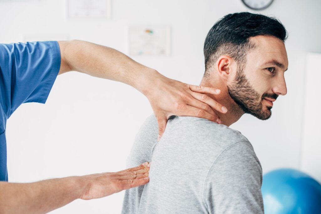 chiropractor massaging neck of good-looking man in hospital